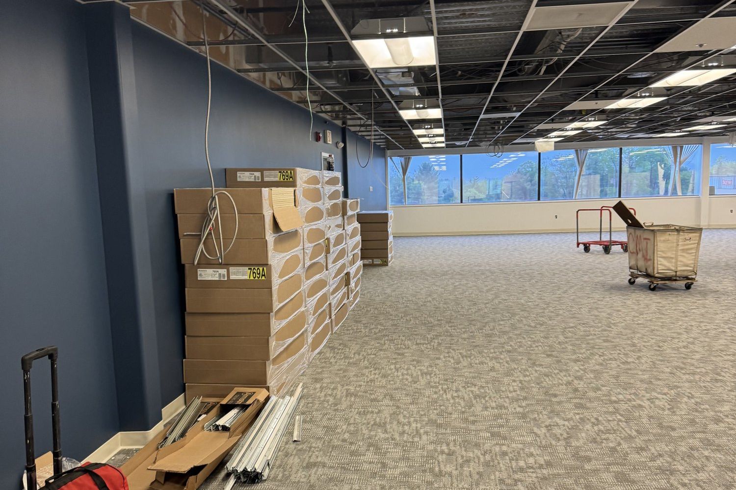Boxed systems furniture components staged against the wall of an empty floor at Tata & Howard during installation
