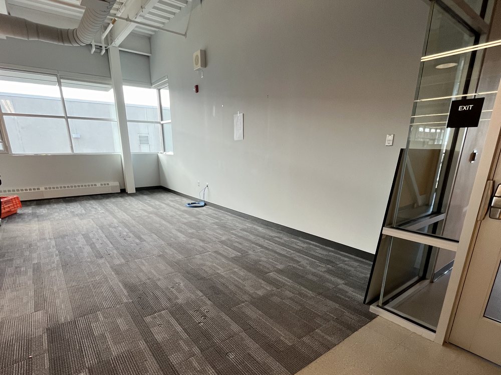 Empty office shell with new carpet tile and a glass entry, ready for the furniture package